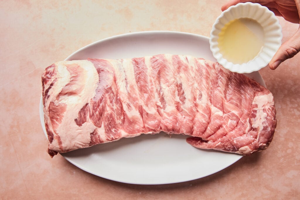 Spreading oil on pork spare ribs.