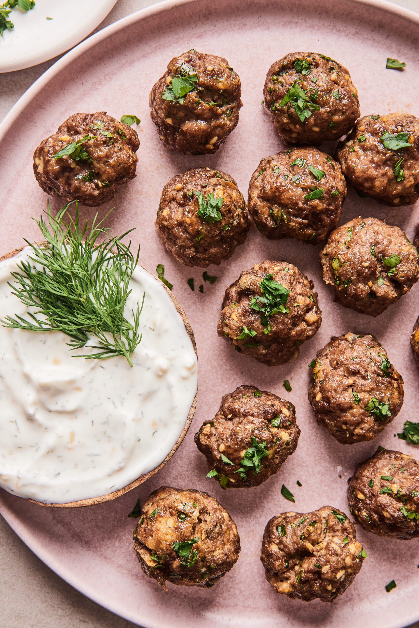 Moroccan meatballs on a plate with yogurt dipping sauce on the side.