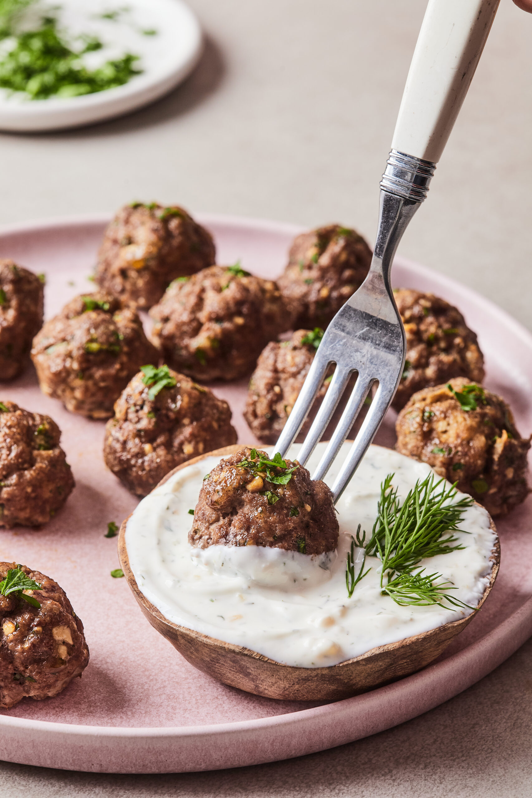 Dipping a meatball into creamy yogurt dipping sauce.