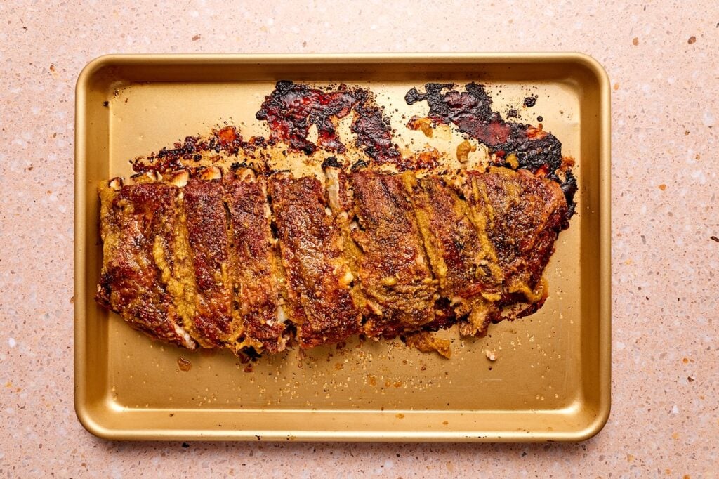 Baked pork ribs on a baking sheet, cut into sections.
