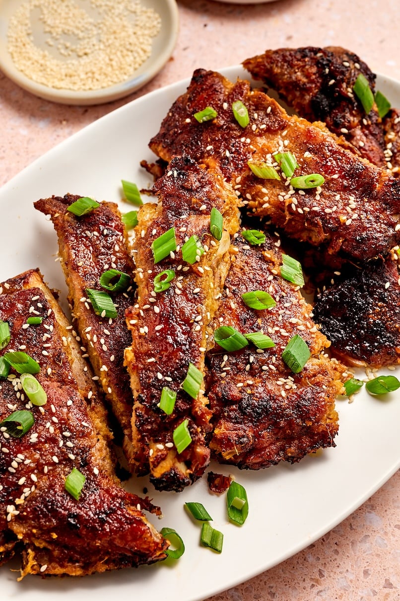 Close up shot of Korean pork ribs garnished with sesame seeds and green onions.