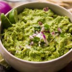 guacamole in a bowl topped with red onions