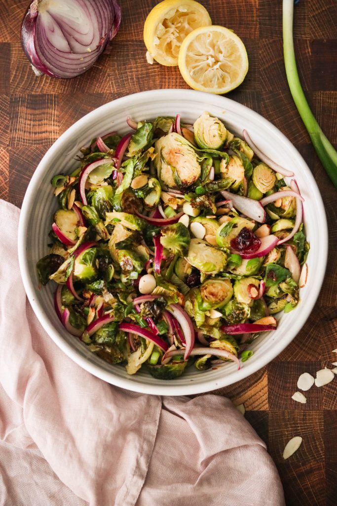 paleo brussels sprouts served in a bowl with almonds, dried cranberries, onions, and more
