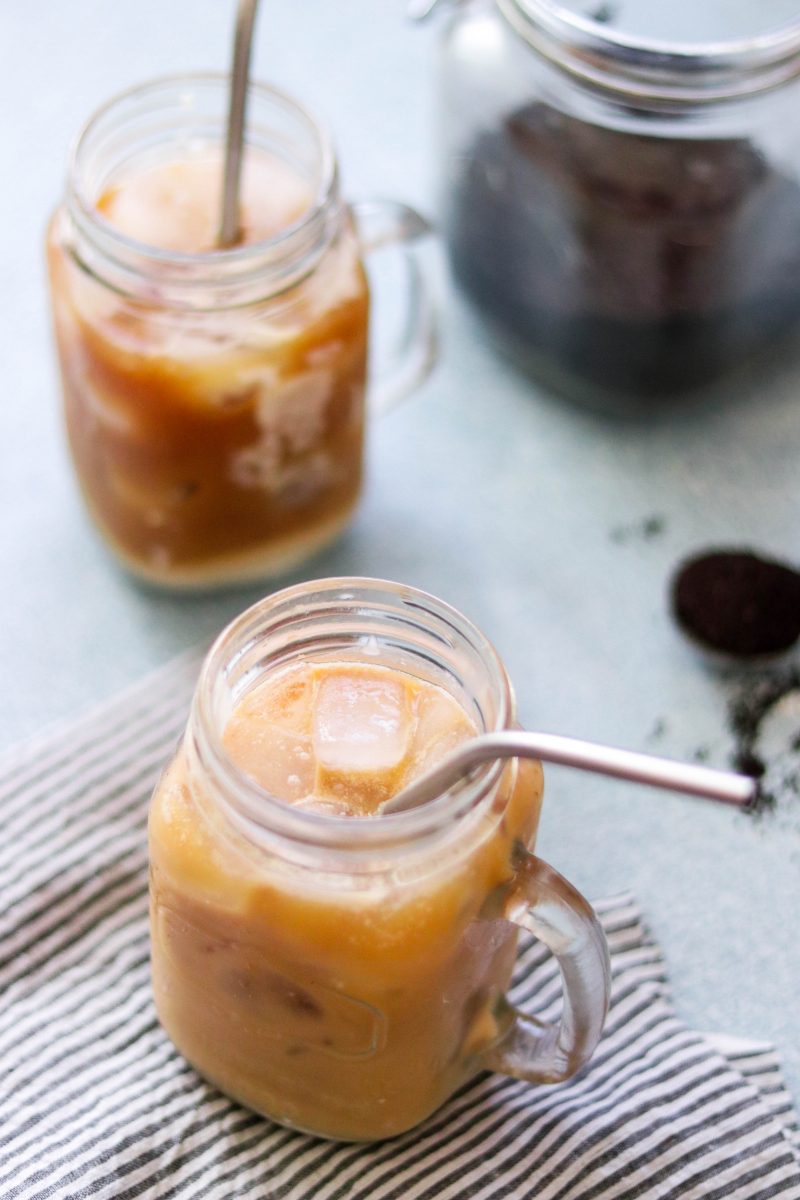 two glass jars with metal straws filled with Thai iced coffee and vegan condensed milk. 