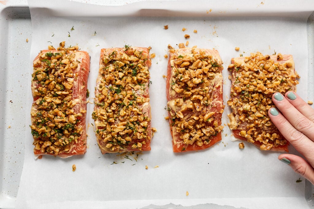 Pressing walnut mixture on top of salmon filets.