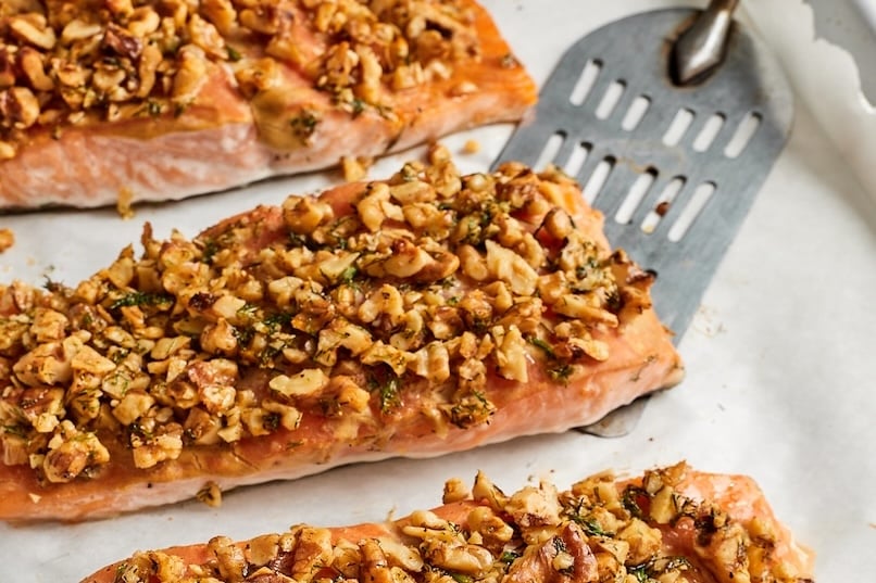 Baked walnut crusted salmon filets on a parchment paper lined baking sheet.