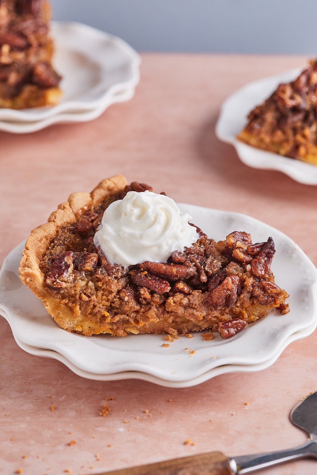 A slice of pumpkin pecan pie on a white plate topped with a dollop of whipped cream
