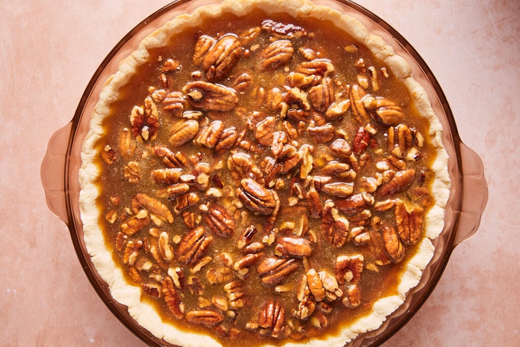 Unbaked pie with pecan layer on top of the pumpkin filling