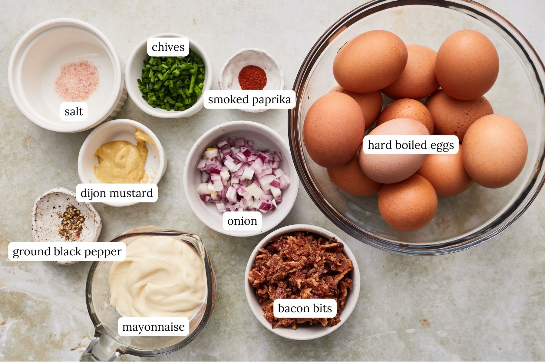 Ingredients for the classic egg salad laid out and labeled on a light gray countertop.