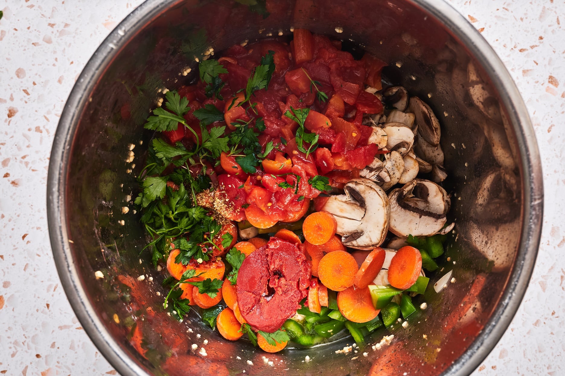Mushrooms, carrot, green bell pepper, diced tomatoes, tomato paste, parsley, thyme, oregano, and red pepper flakes in the Instant Pot.
