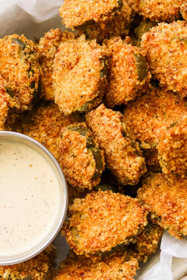 an up close photo of keto fried pickles on a platter next to a small bowl of ranch