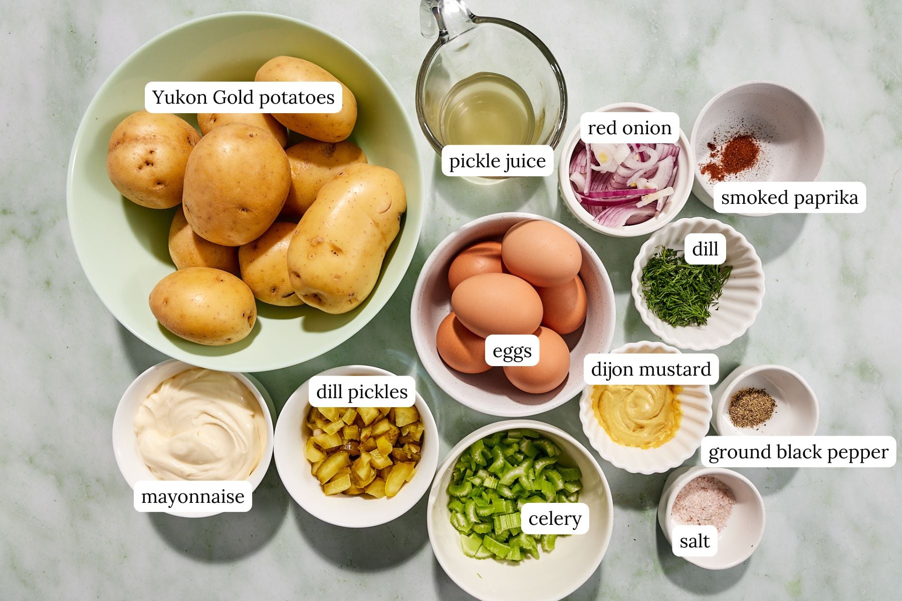 Ingredients for potato salad in small bowls and labeled