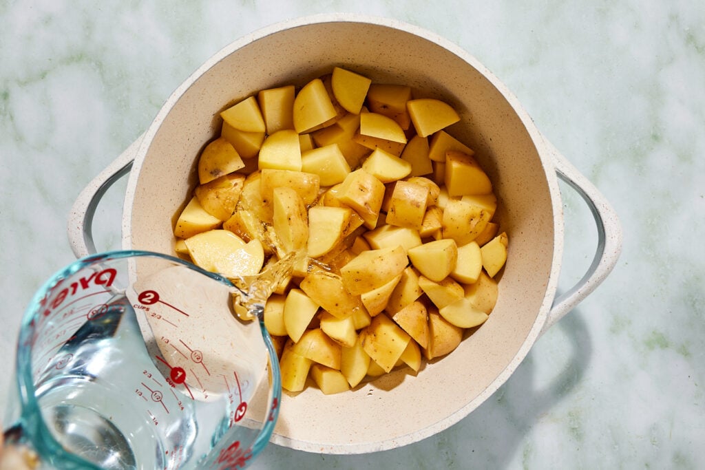 Pouring water in a pot of Yukon gold potatoes before boiing