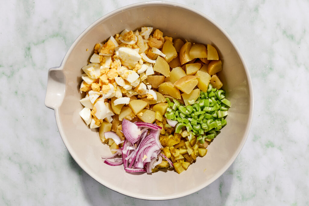 Combining ingredients for dill pickle potato salad in a large bowl