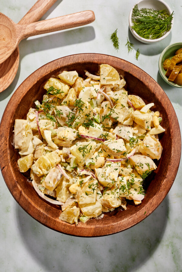 Whole30 dill pickle potato salad in a large wooden bowl, garnished with dill