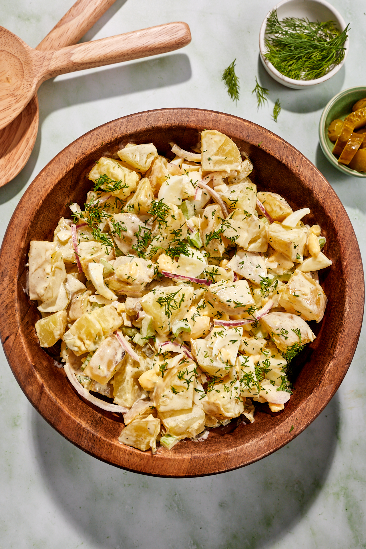 Whole30 dill pickle potato salad in a large wooden bowl, garnished with dill