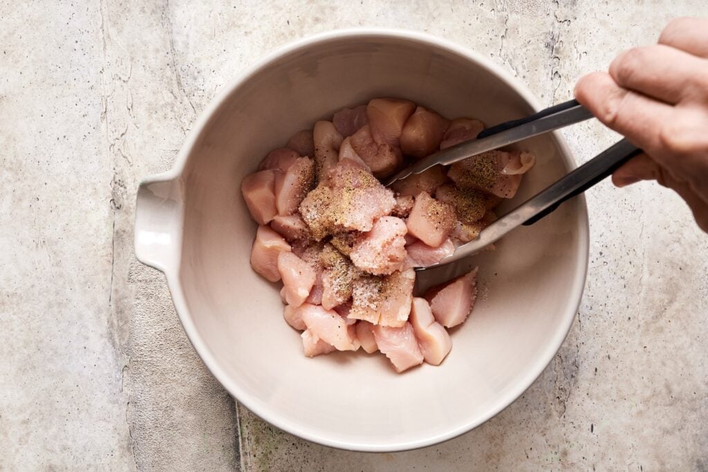 tossing chicken pieces with salt and pepper