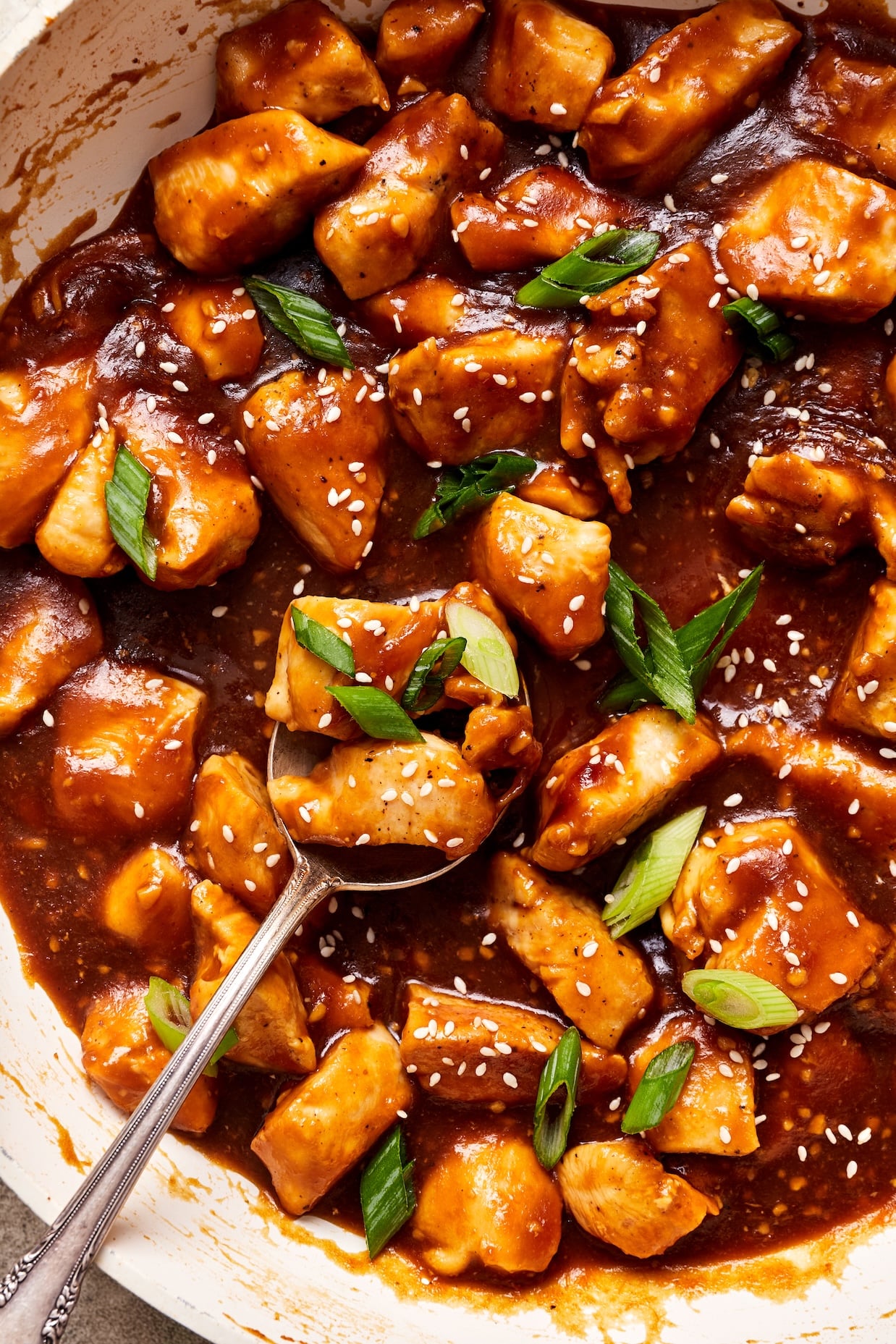 close up shot of cooked teriyaki chicken in a skillet garnished with green onions and green onions