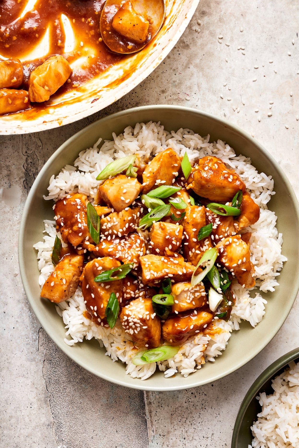pineapple teriyaki chicken in a bowl with rice, green onions, and sesame seeds
