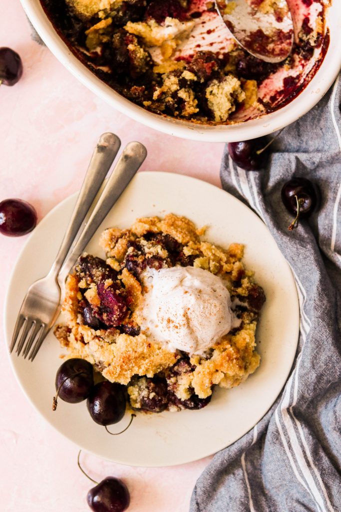 paleo cherry crumble on a plate with vanilla ice cream on top