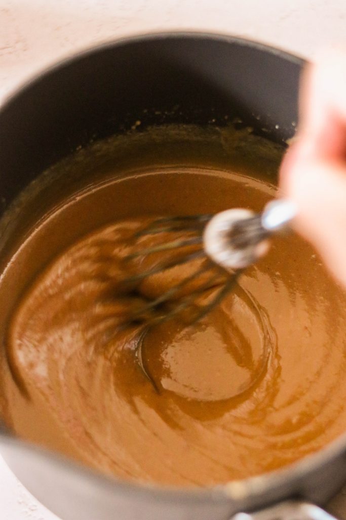 heating up and whisking easy caramel sauce in a saucepan