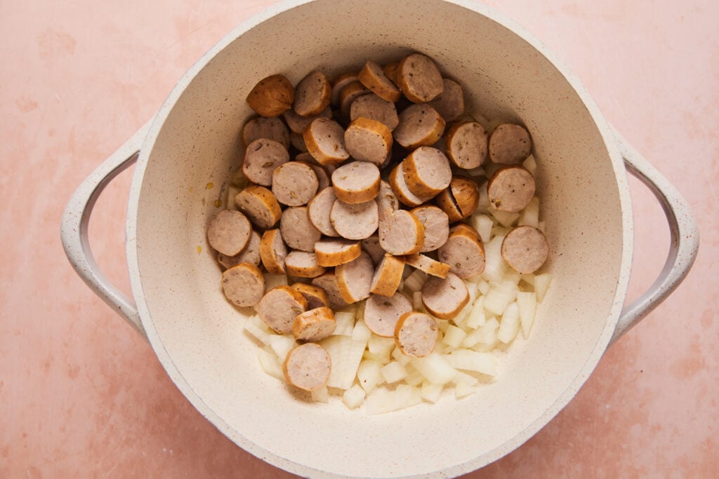 onions and sausage cooking in a dutch oven