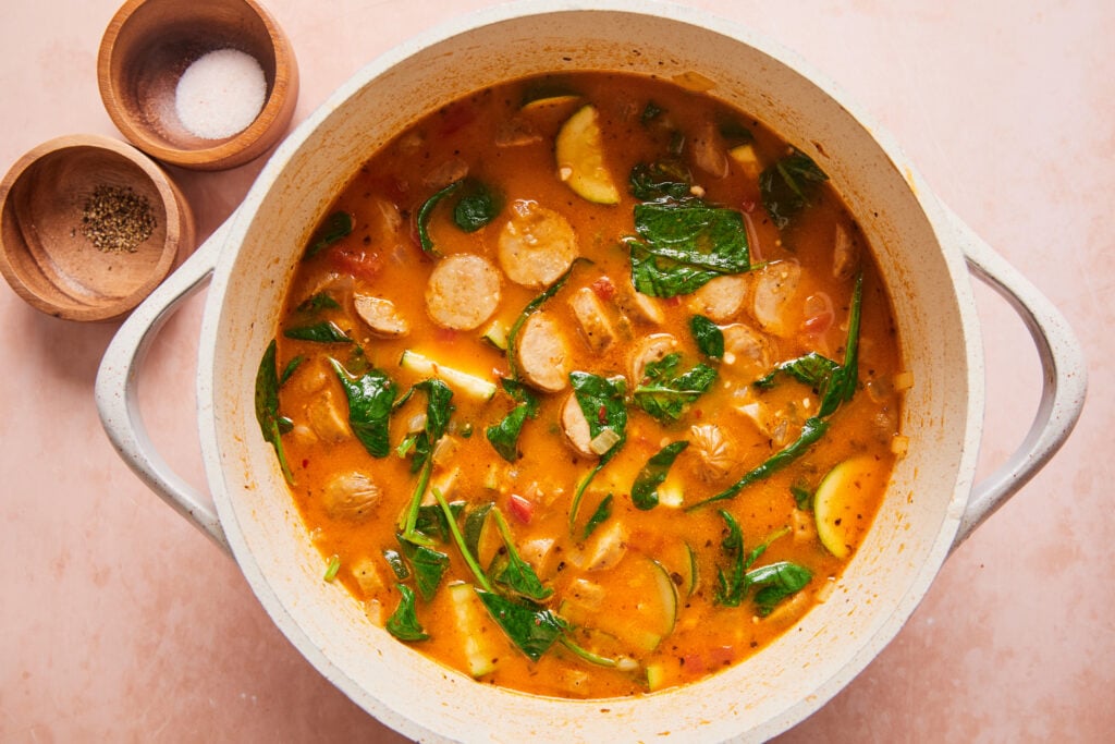 adding spinach and coconut milk to the soup at the end