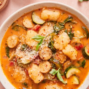 italian sausage and gnocchi soup in a white bowl with a spoon