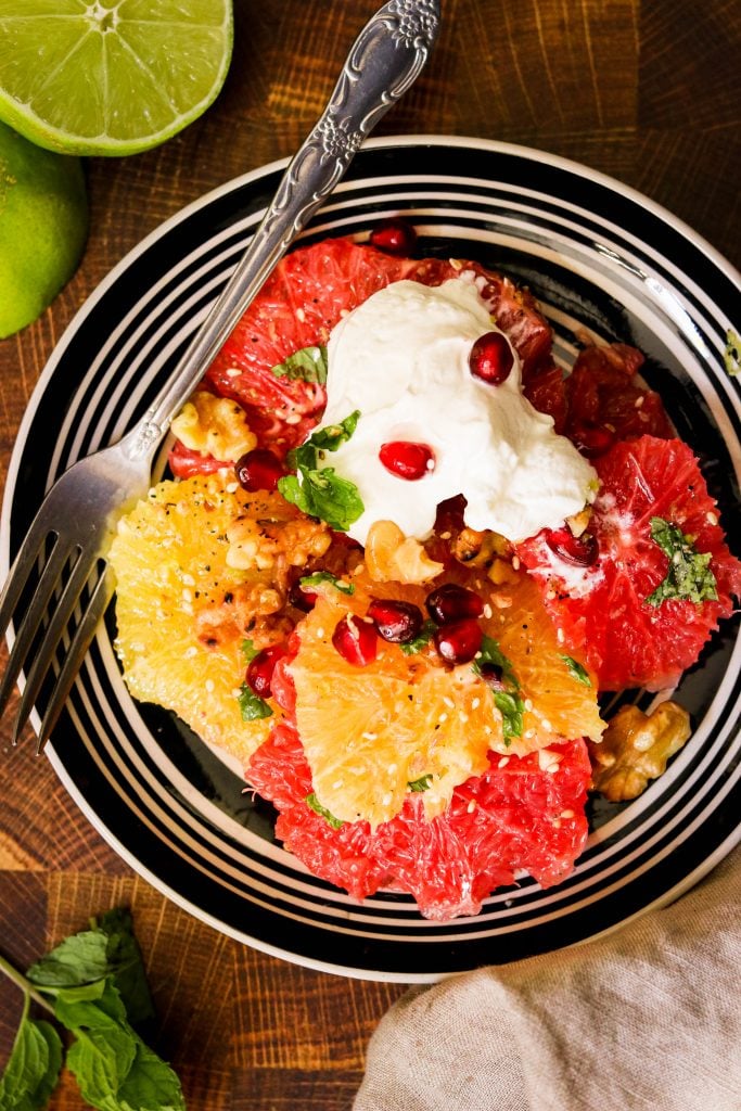 paleo winter salad with citrus on a plate ready to eat with a fork