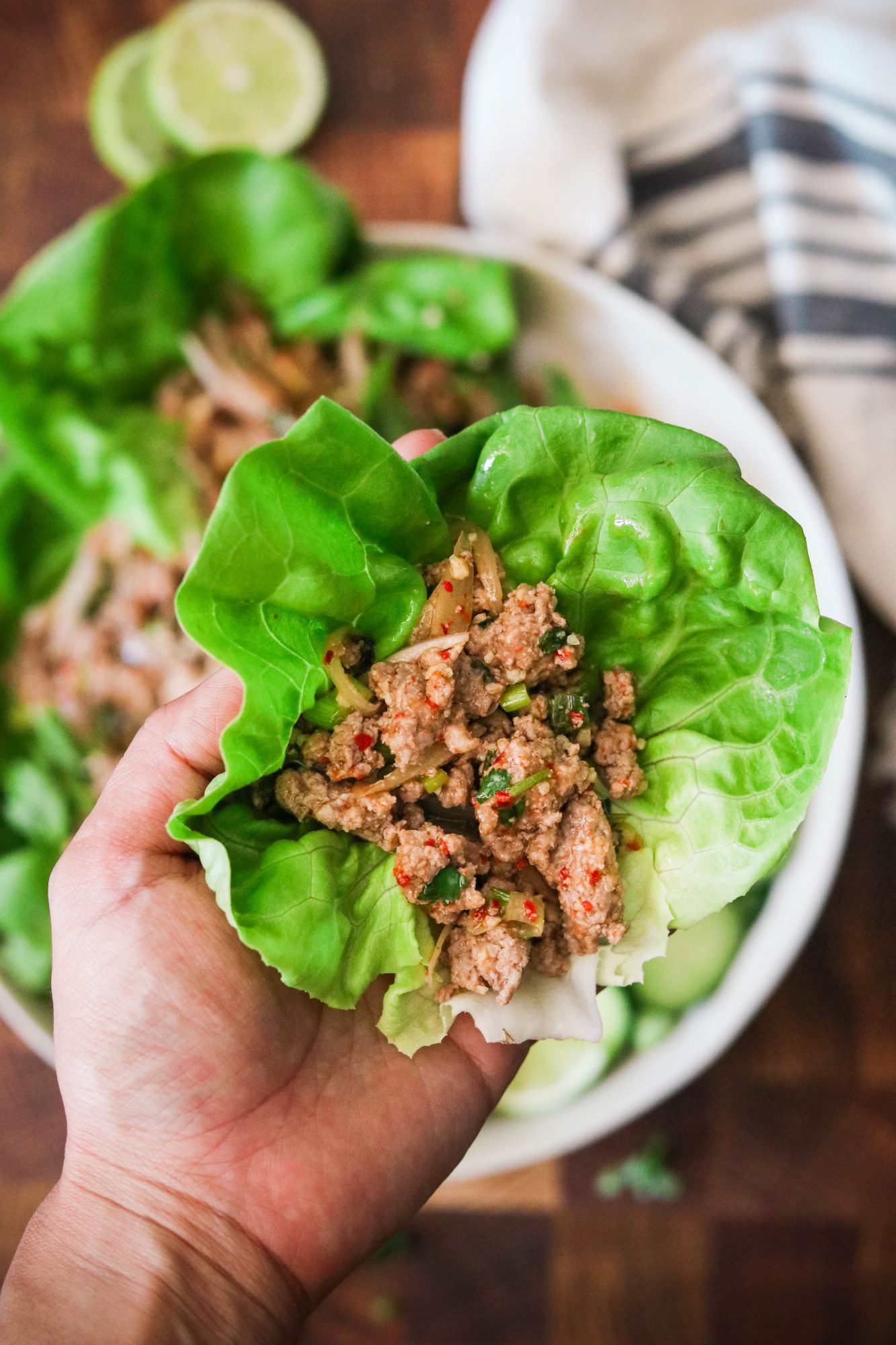 Hand lifting up larb moo in a lettuce wrap