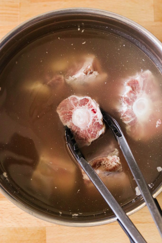Cleaning oxtail in water to draw out blood