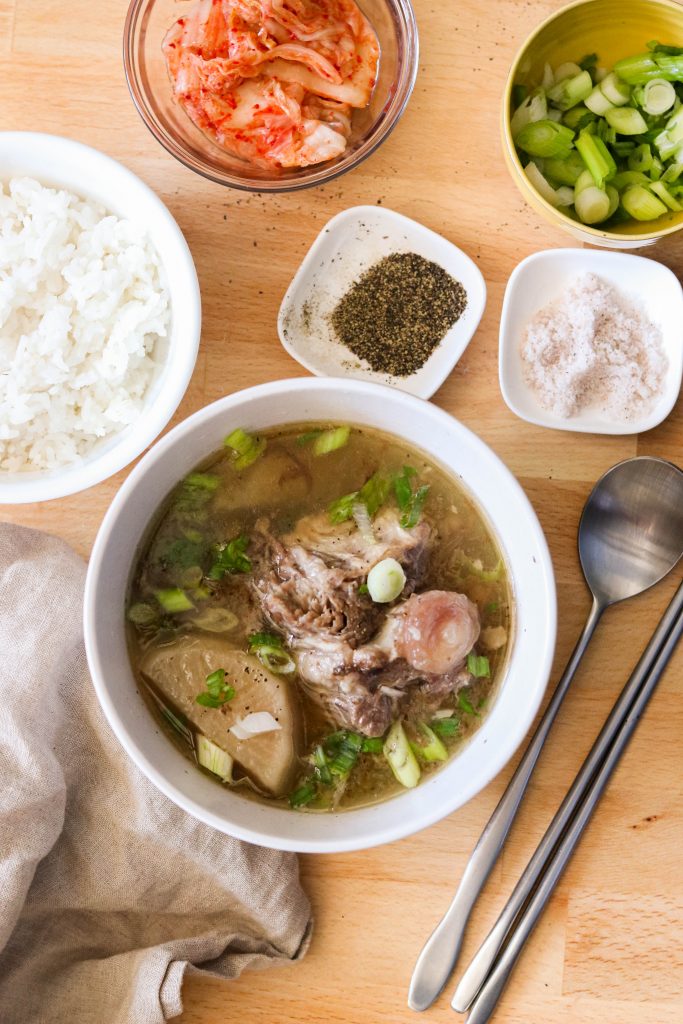 Korean oxtail soup recipe served with salt, pepper, green onions, kimchi, and rice