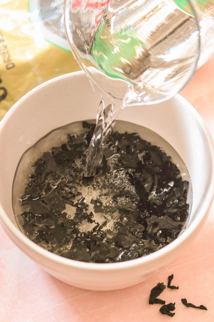 pouring warm water over wakame to reconstitute and hydrate the leaves