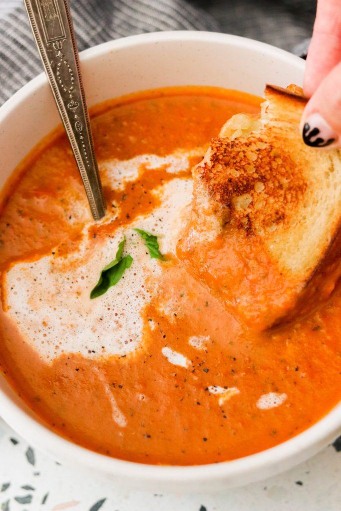 dipping grilled cheese into a bowl of soup