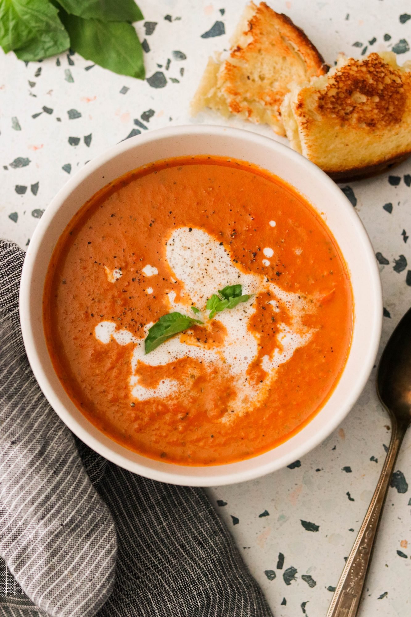 Whole30 tomato soup in a bowl, garnished with basil
