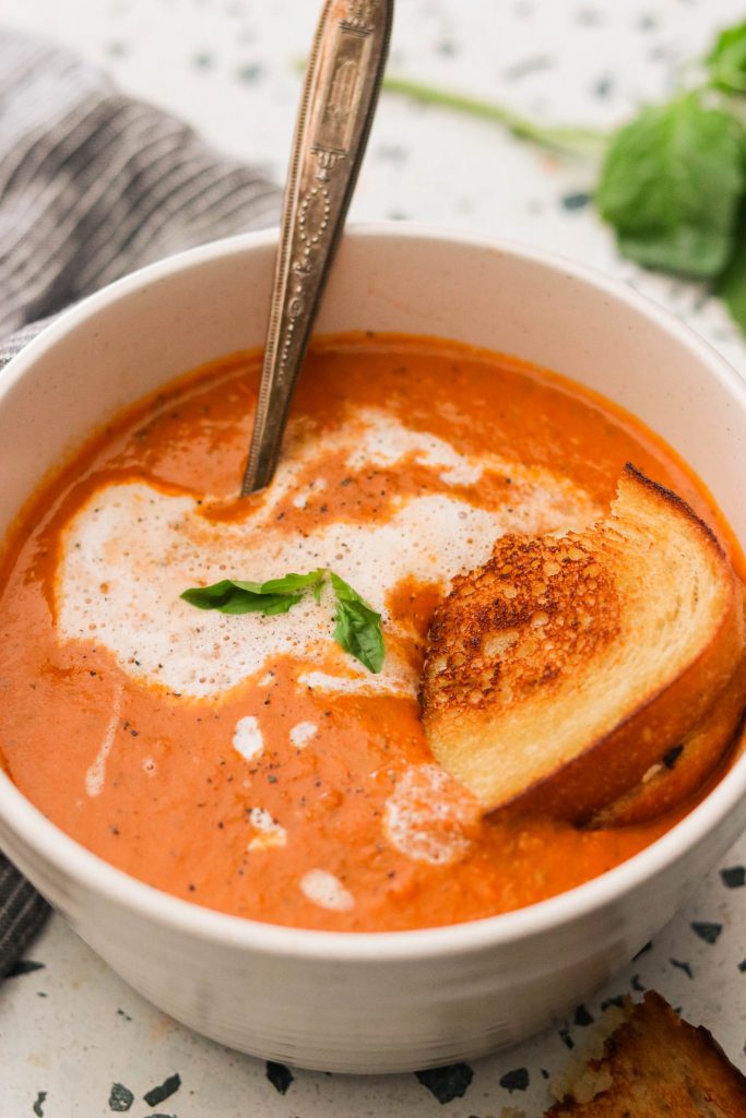 paleo roasted tomato soup drizzled with coconut milk, served with grilled cheese