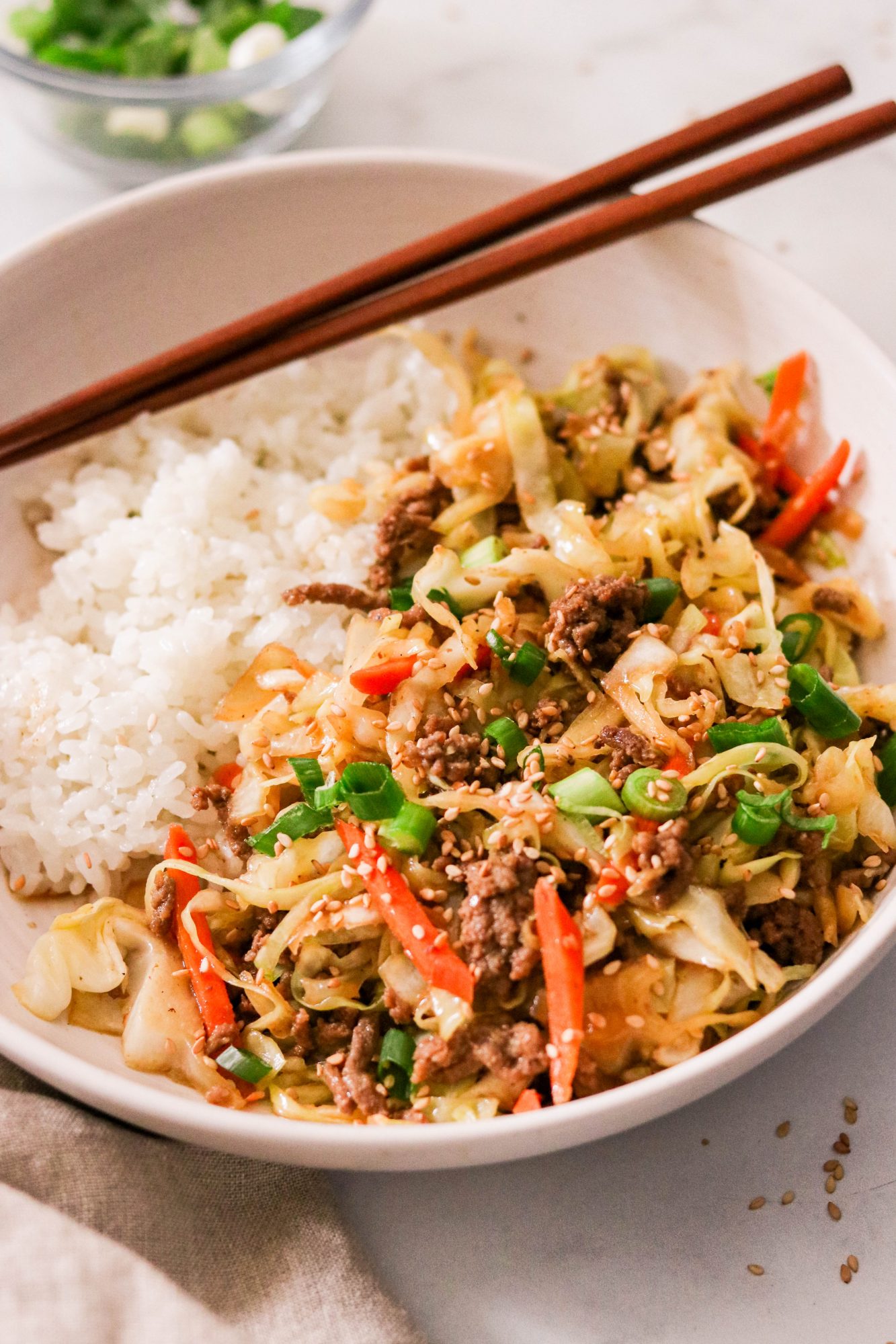 whole30 beef stir fry recipe in a bowl with rice and chopsticks