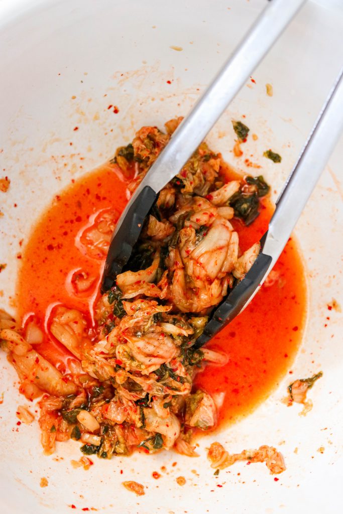Kimchi in a mixing bowl tossed with spices