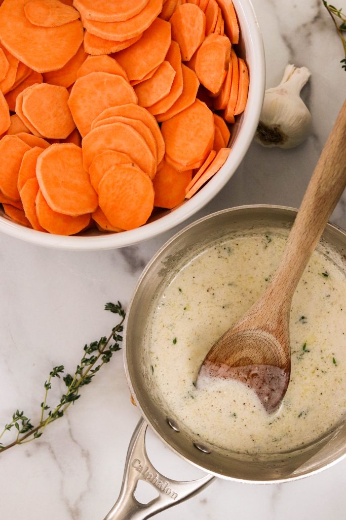 sliced sweet potato rounds in a bowl next to garlic cream sauce