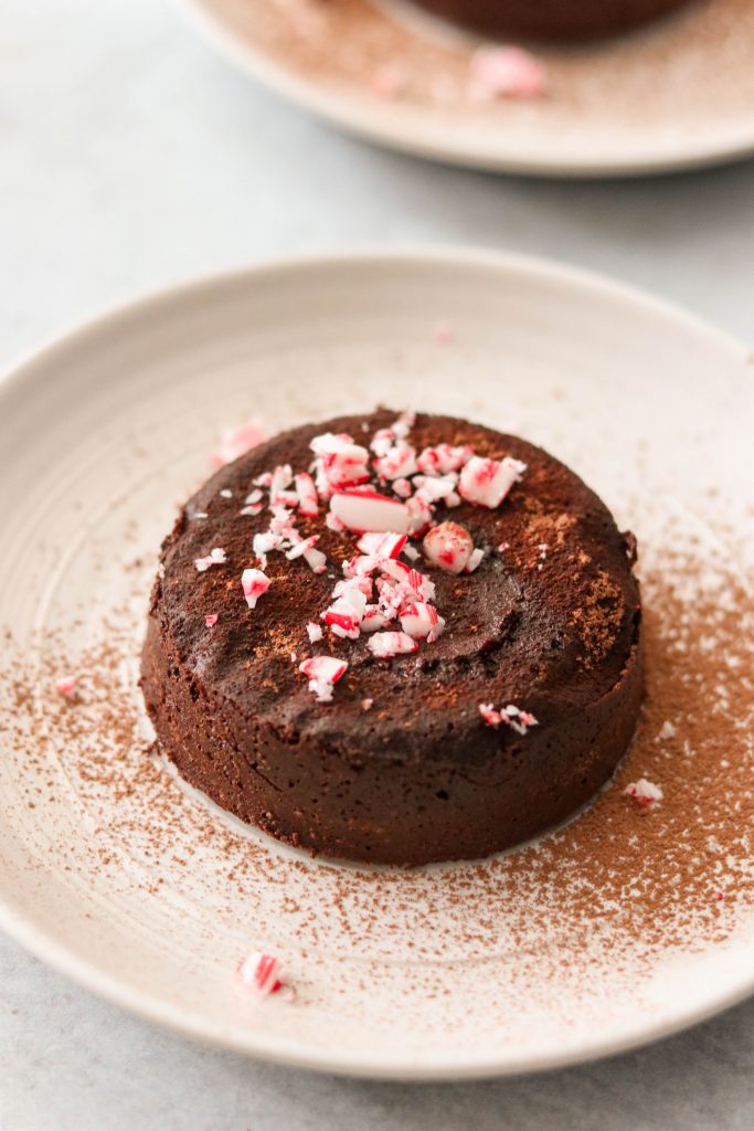 paleo gluten free chocolate lava cake served on a plate with candy canes and cocoa powder