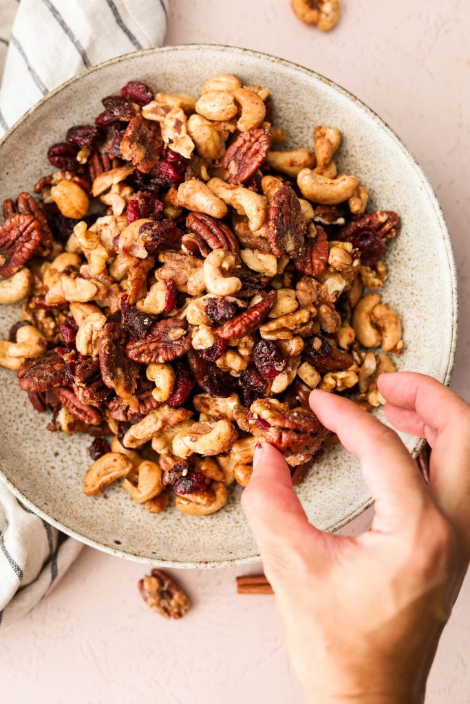 hand lifting up a cluster of holiday spiced nuts