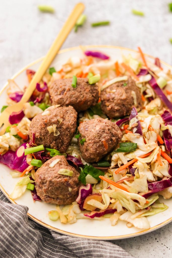 Asian meatballs served over slaw mix, garnished with green onions