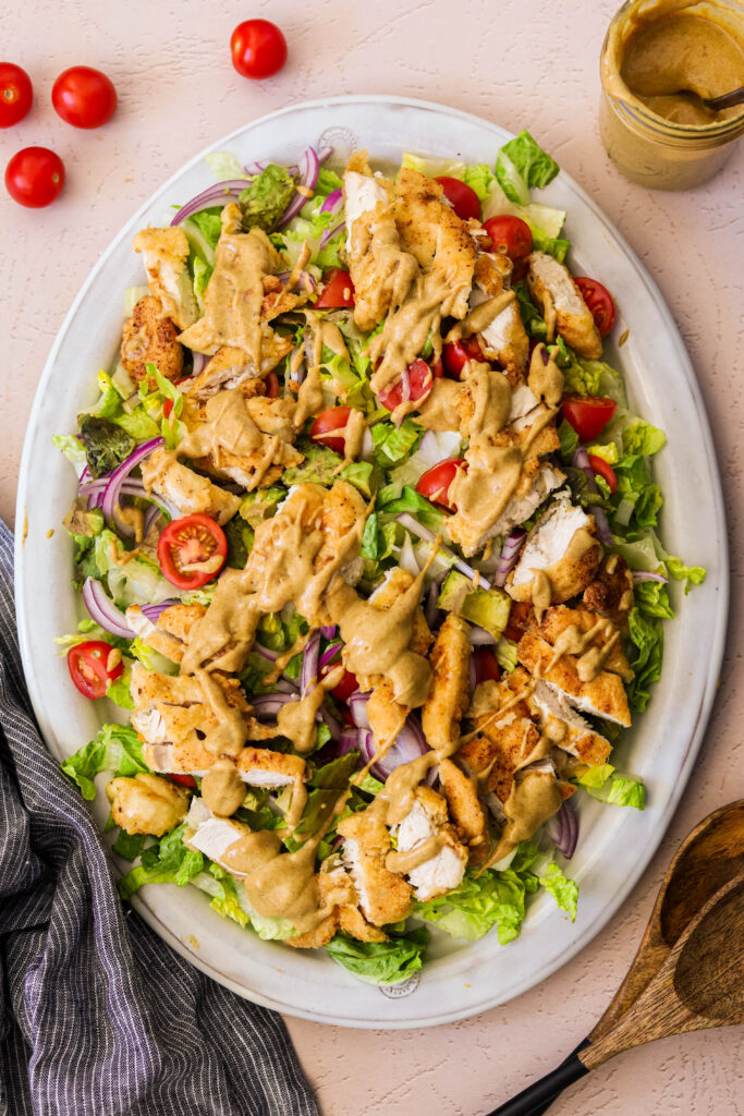 paleo crispy chicken salad served on a platter topped with honey mustard dressing