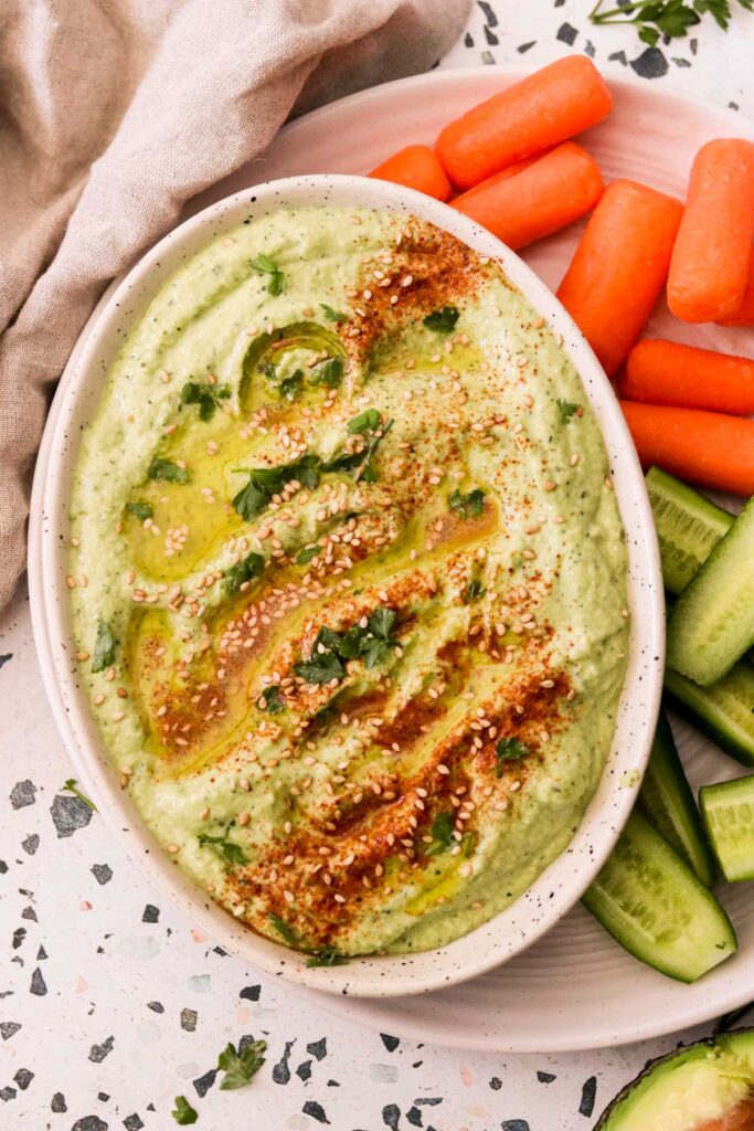raw zucchini hummus served with carrots and cucumbers.