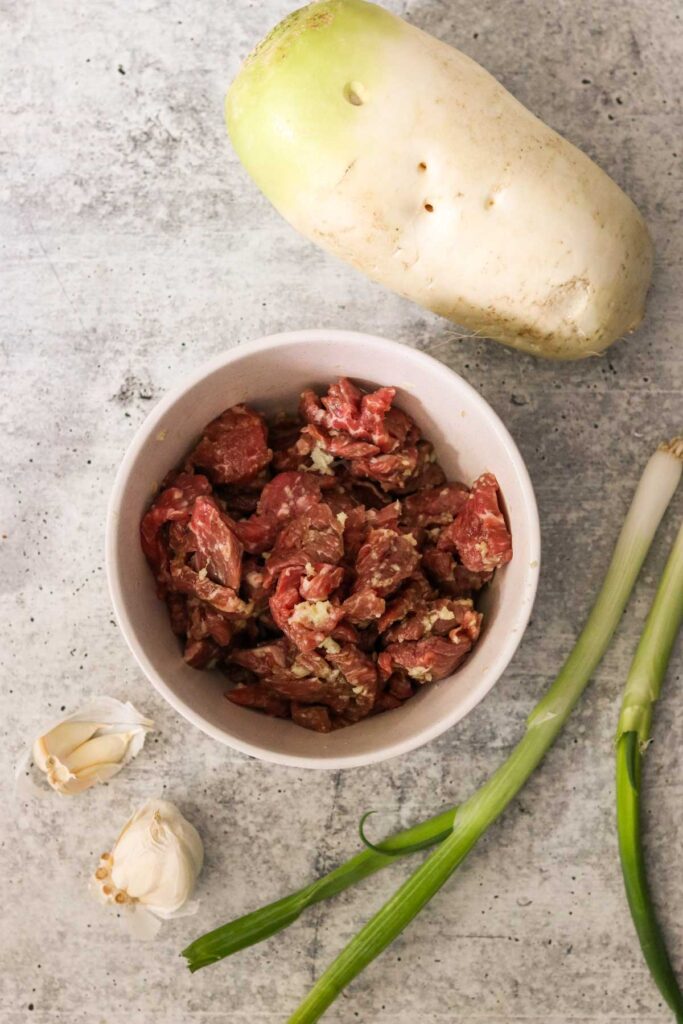 Ingredients for muguk: beef brisket, mu, green onions, and garlic
