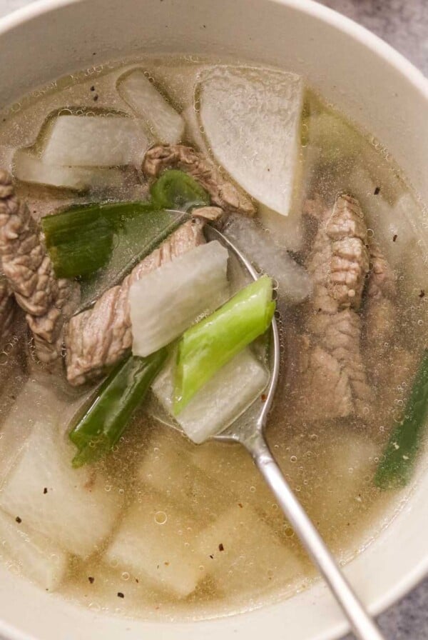 Korean radish soup, or muguk, in a bowl with a spoon