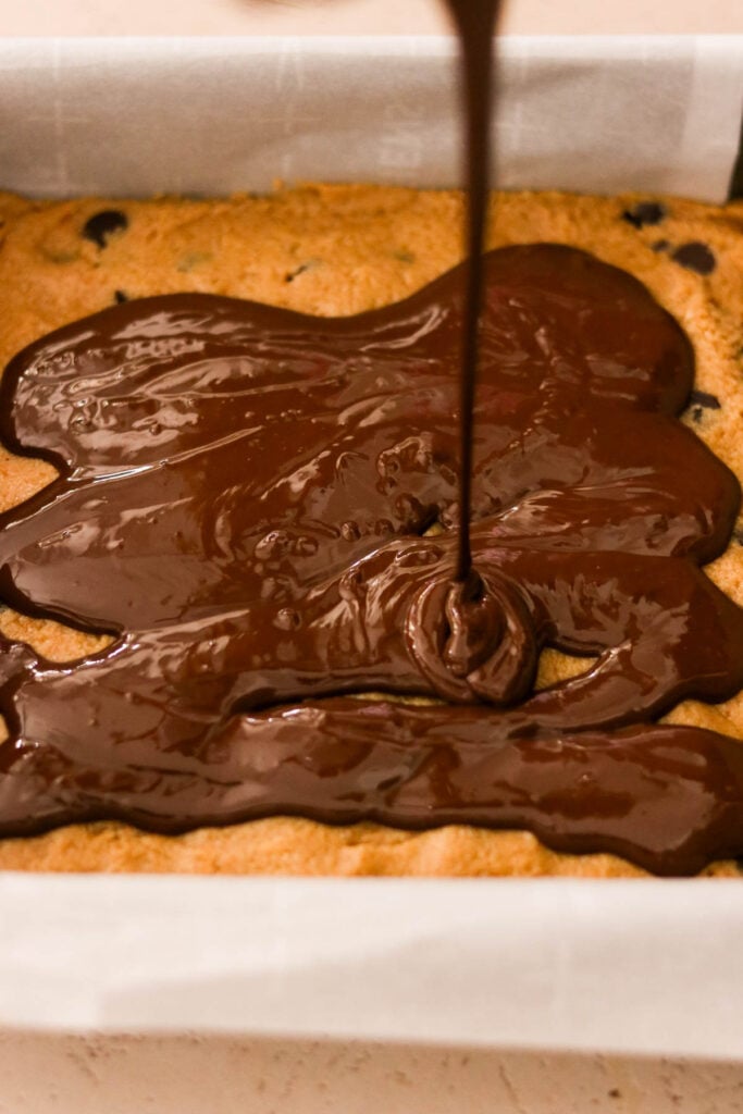 Pouring melted chocolate over the peanut butter layer