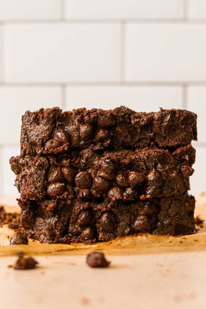 Gluten free chocolate zucchini bread slices stacked on parchment paper.