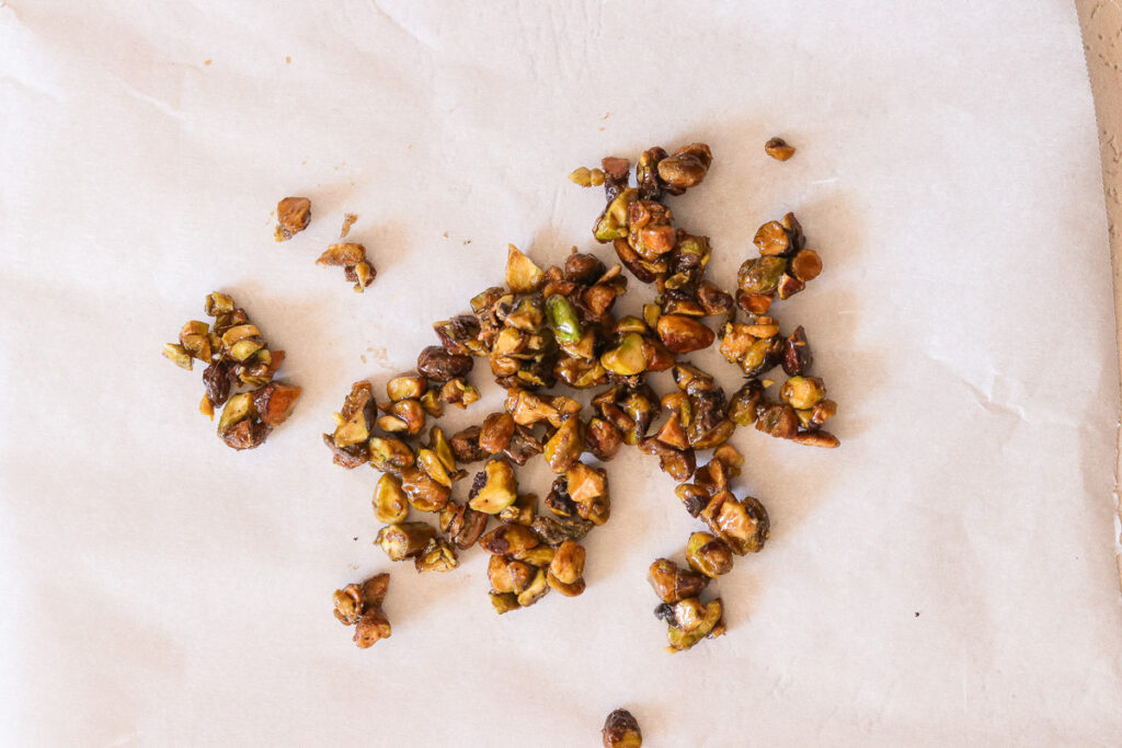 caramelized pistachios cooling on parchment paper