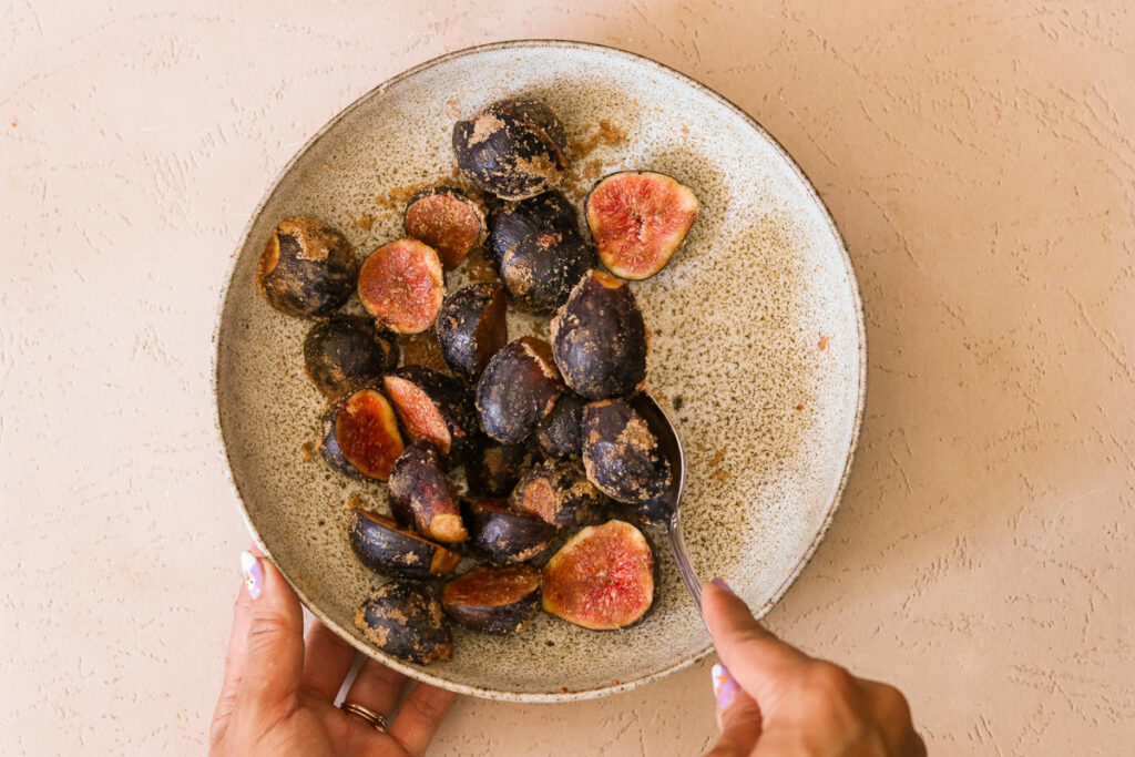 Fig halves in bowl tossed with brown sugar and cinnamon
